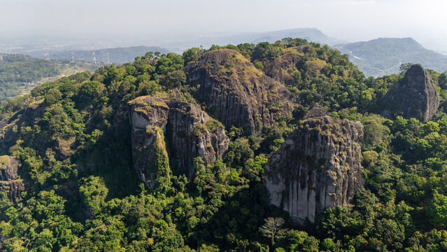 Aerial view of Ancient Volcano Nglanggeran with rugged rock formations and lush green forest canopy in Kecamatan Patuk, Daerah Istimewa Yogya, Indonesia.