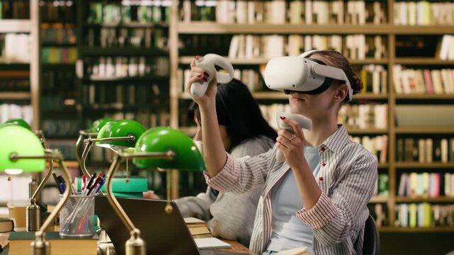 Student using virtual reality headset and hand controllers at library desk, blending interactive digital learning with books and modern research tools.