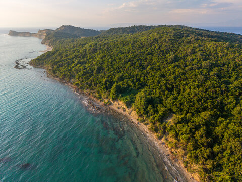 Aerial coastal landscape of a green forested hillside, narrow beach and calm blue sea at Kepi i Rodonit, Albania.