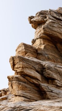 Massive weathered layered rock formation standing against clear sky showcasing intricate natural textures and geological features in a desert environment