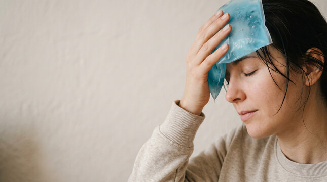 Woman holding ice pack on forehead to cool down from summer heat. Young girl suffering from heatstroke and high fever. Healthcare and medical symptom treatment for heat exhaustion.
