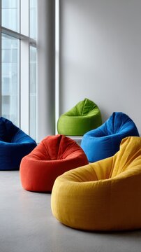Colorful bean bag chairs arranged in a modern room with large windows providing natural light and a minimalist open space design for relaxation or socializing
