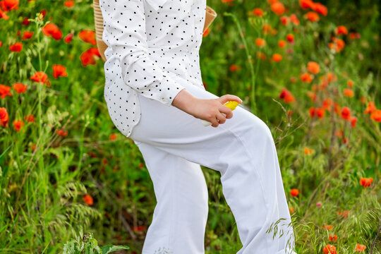Woman spraying antitick chemical protection on clothes. Safe summer hiking guidelines and body defense against insect bites and lyme disease vectors.