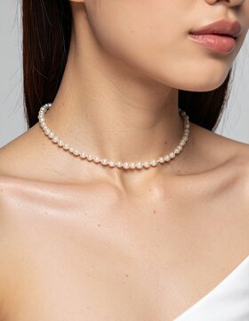 Close-up of a woman wearing a classic white pearl choker necklace, studio lighting on skin, elegant jewelry, minimalist accessories, fashion retail.