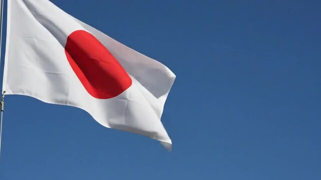 The national flag of japan waving against a clear blue sky
