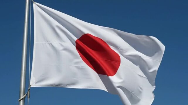 The national flag of japan waving against a clear blue sky