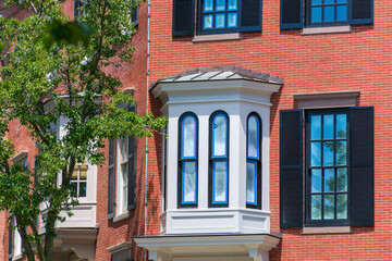 Obraz premium Bay window with arched windows on red brick residential building facade in Charlestown Boston, USA 