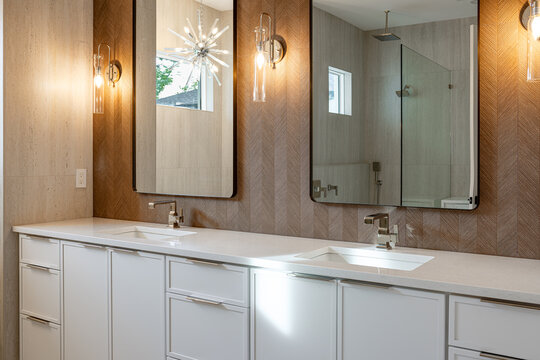 Modern luxury bathroom vanity with double undercounter sinks chrome faucets large mirrors and elegant wall sconce lighting
