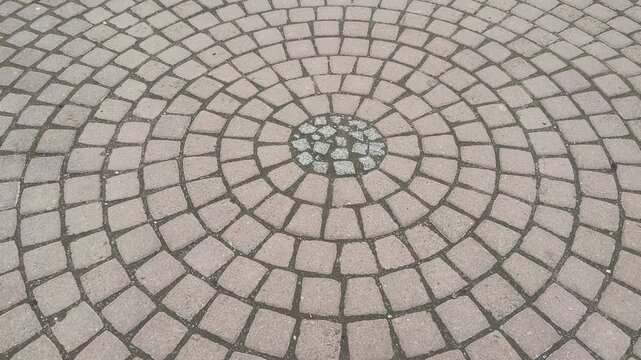 Top view paving stones circular mosaic, closeup overhead shot of concentric cobble rings with beige tiles, gravel filled joints