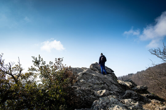 A man is looking at a view from the top of a mountain