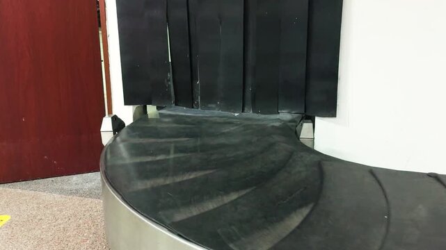 Empty airport baggage carousel conveying passengers' luggage in the arrival terminal, emphasizing travel, transportation, logistics, and the process of international and domestic journey completion