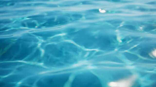 Crystal clear blue swimming pool water surface texture with sun reflections and gentle ripples for summer backgrounds and relaxation concepts