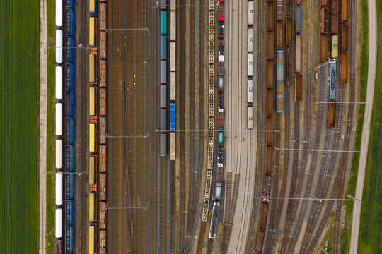 Aerial view of a busy railway yard with various freight trains, cargo containers, and tracks arranged in parallel lines in Breclav, South Moravian Region, Czechia.