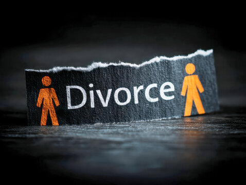 Torn paper with symbolic orange male and female figures representing separation and divorce concept on dark surface background