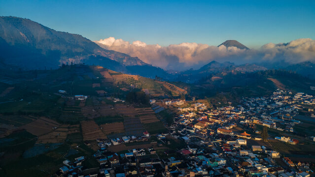 Aerial view of Bukit Skoter overlooking the town of Kecamatan Batur with terraced fields and distant mountains in Kecamatan Batur, Jawa Tengah, Indonesia.