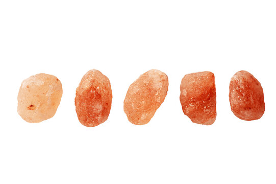 Five natural pieces of raw Himalayan pink salt rocks arranged in row. Organic mineral crystals used for cooking and wellness, isolated on white background.