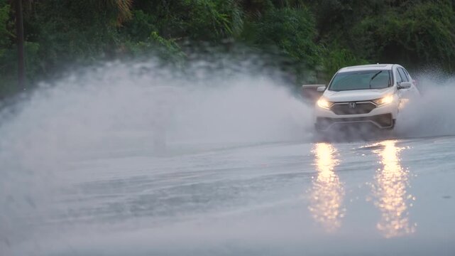 Hurricane rainfall flooded Florida road with evacuating cars and surrounded with water houses in suburban residential area.