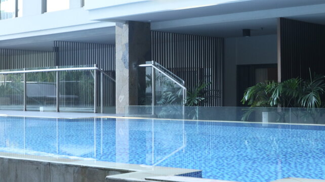 The atmosphere of the swimming pool with clear water on the ground floor of the hotel. There are shady trees, nice for relaxing.