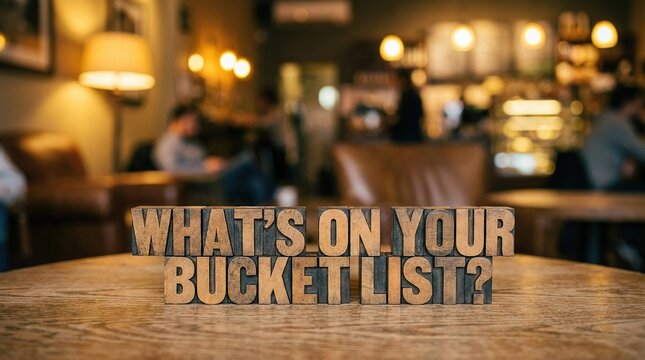 Wooden blocks spelling out 'what's on your bucket list' on a table in a cozy cafe environment with warm lighting