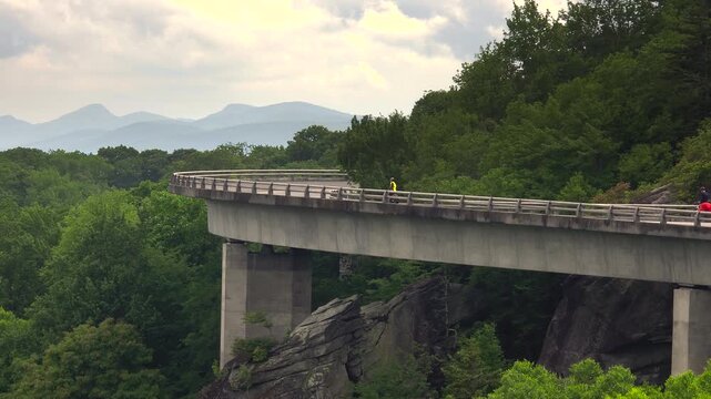 Biking on mountain road in summer woods. Cyclists on Linn Cove Viaduct in Appalachian mountains in North Carolina with fresh green forest trees in summertime season. Beauty of USA nature.