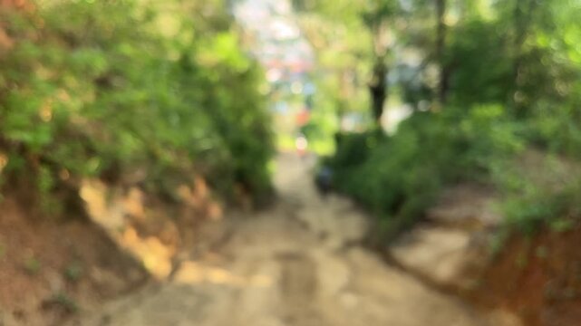 Blurred background of person descending steep mountain trail in forest
