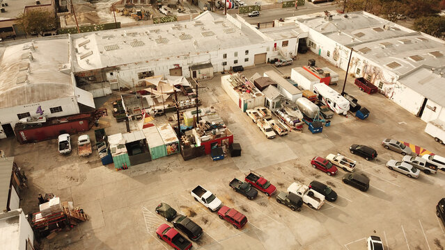 Aerial view of Big Art Labs with industrial warehouses, parked cars, shipping containers, and creative workspaces in Los Angeles, California, United States.