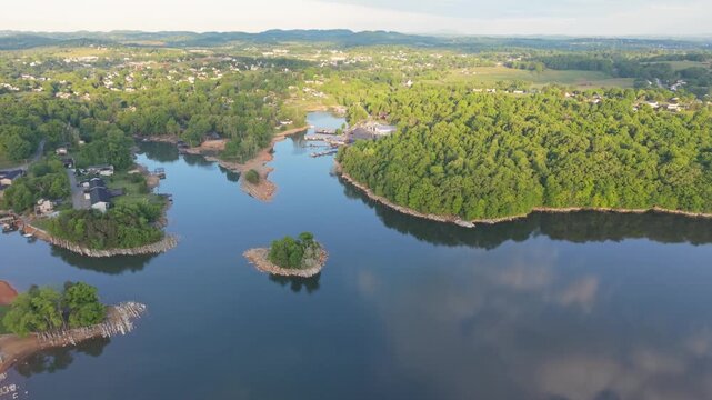 Aerial perspective of Johnson City, Tennessee, reveals a peaceful lake bordered by vibrant green trees, small islands, and nearby homes, illustrating the harmonious blend of nature community in area