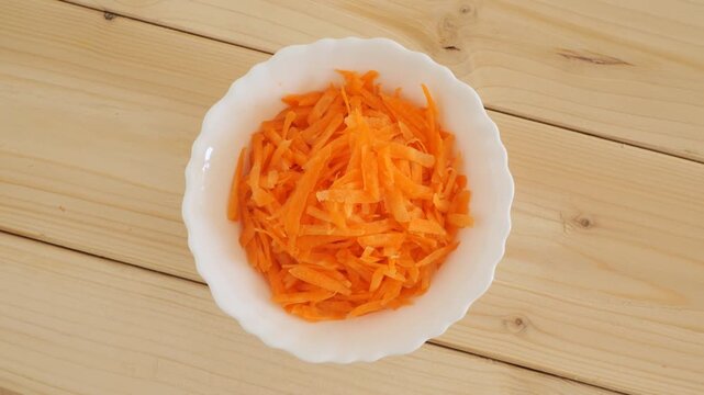 White bowl of grated carrots rotating