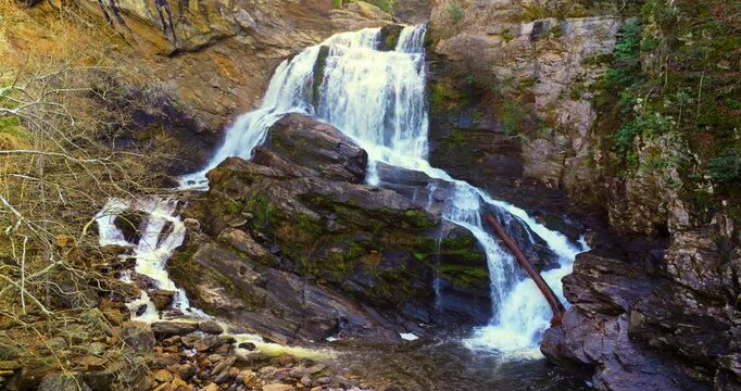 Beautiful waterfall in Appalachian mountains. Autumn beauty at Cullasaja Falls in Nantahala National Forest. Rushing river water and steep cliffs bordered by colorful deciduous trees