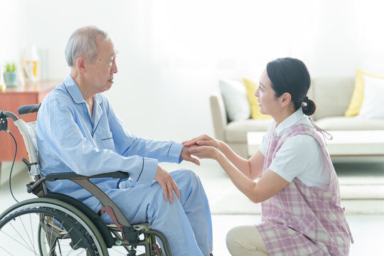車椅子に乗った高齢者をサポートする介護士
