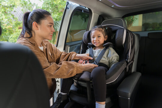 mother is fastening safety belt to preschool child girl in car seat, safety baby chair travelling