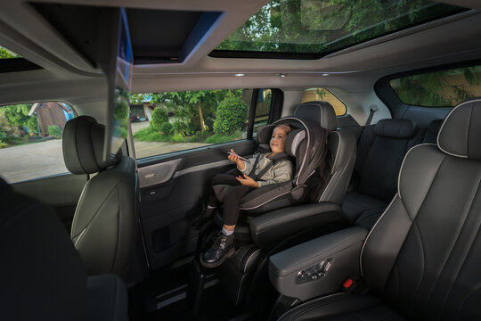 preschool child girl watching rear entertainment screen or ceiling screen while sitting in car seat, safety baby chair travelling