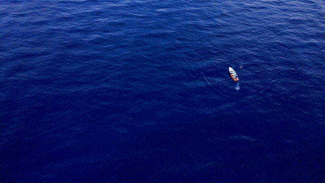 Aerial view of a small boat floating on the deep blue ocean surface in Trou-aux-Biches, Pamplemousses District, Mauritius.