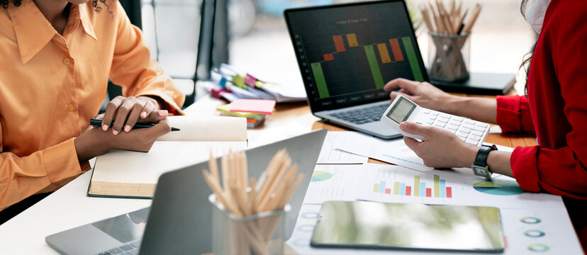 Businesswomen analyzing financial charts and data on laptop in the office