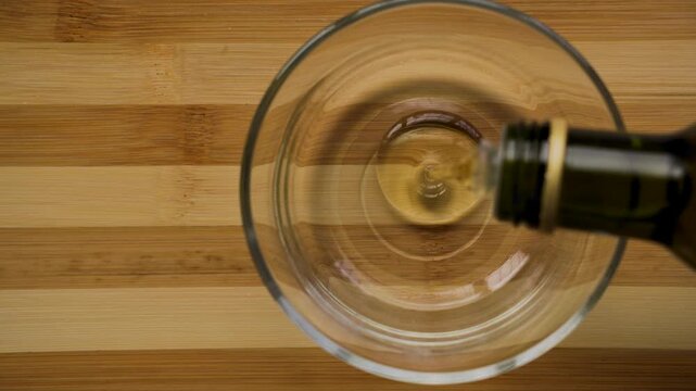 Pouring organic olive oil into glass bowl top down view 4k