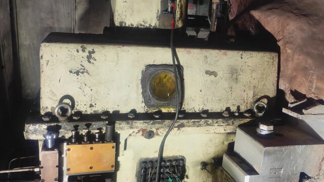 Close up view of a heavy industrial mechanical unit featuring a robust metal housing lubrication components control fittings and weathered surfaces inside an industrial machinery environment