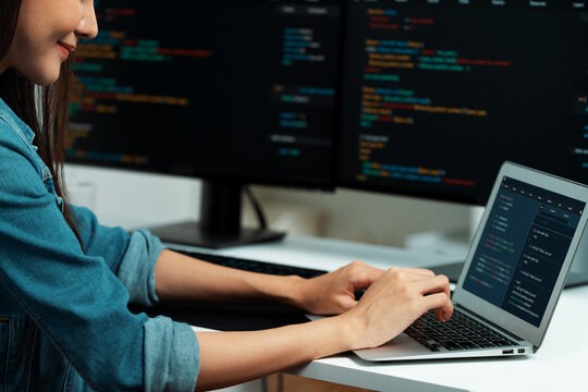 Smiling young Asian in IT developer creating with typing online information on laptop with coding program data of application, wearing jeans shirt. surrounded by safety analysis two screen. Stratagem.