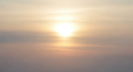 Fototapeta premium Bright golden sun shining through soft morning clouds at sunrise.