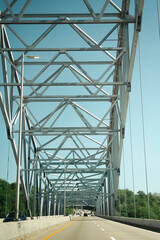 Fototapeta premium View from a moving vehicle driving across a steel truss bridge in Kentucky beneath an intricate network of structural steel beams. The dramatic perspective emphasizes the bridge's geometric design