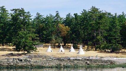 four white teepees in a campground close to the water © CP Studios