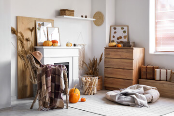 Obraz premium Interior of stylish living room with fireplace, armchair and pumpkins. Autumn concept