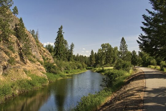 Sunny summer day view of the Trail of the Coeur d&rsquo;Alenes passing beside a rocky cliff and small pond in the forest near Harrison, Idaho.