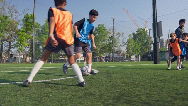 Young boy dribbling football during competition on outdoor soccer field. 