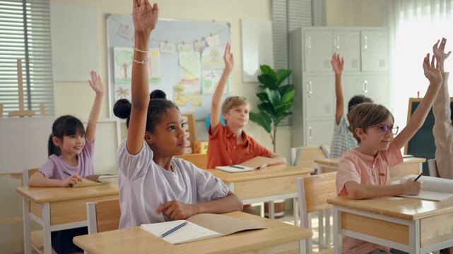 Group of diverse students raising hands to answer questions in classroom. 