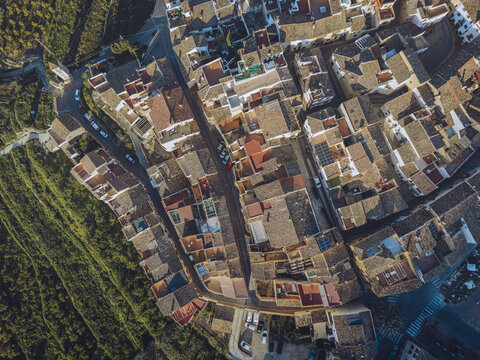 Aerial view of the historic town with its dense cluster of terracotta rooftops, narrow winding streets, and surrounding terraced hillsides in Barony of Polop, Valencian Community, Spain.
