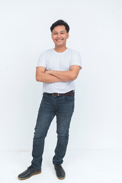 A young Filipino man smiles confidently while standing in an arms crossed pose, wearing casual clothes against a clean studio background.