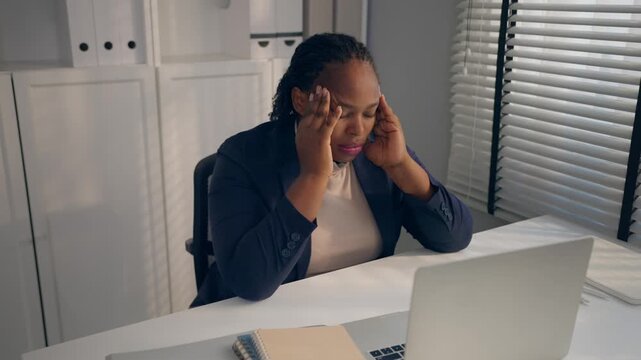 Tired African plus-size businesswoman working in modern office. 