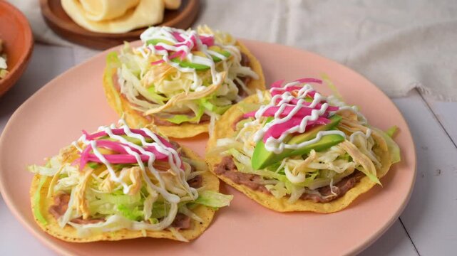 Traditional Mexican tostadas with shredded chicken, lettuce, and cream on a plate