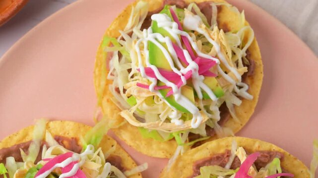 Textures of Mexican gastronomy. Chicken tostadas on a pink plate