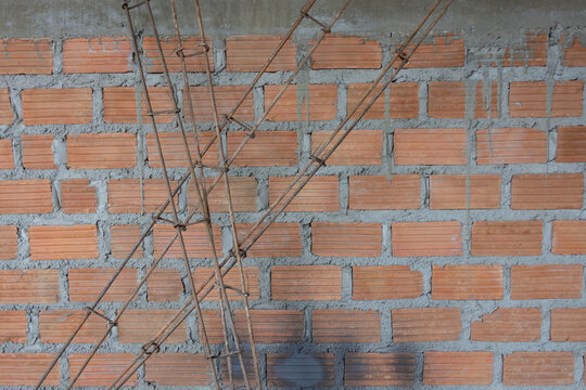 A high-angle, full-frame shot of numerous red clay bricks stacked randomly, illuminated with a slightly pinkish light